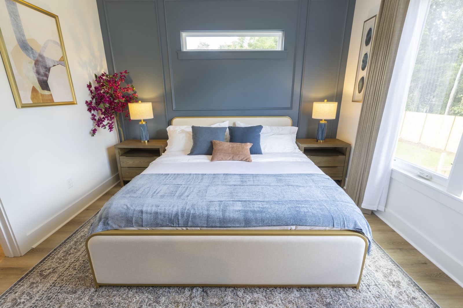 Bedroom with a deep blue paneled wall, upholstered bed, and brass lamps