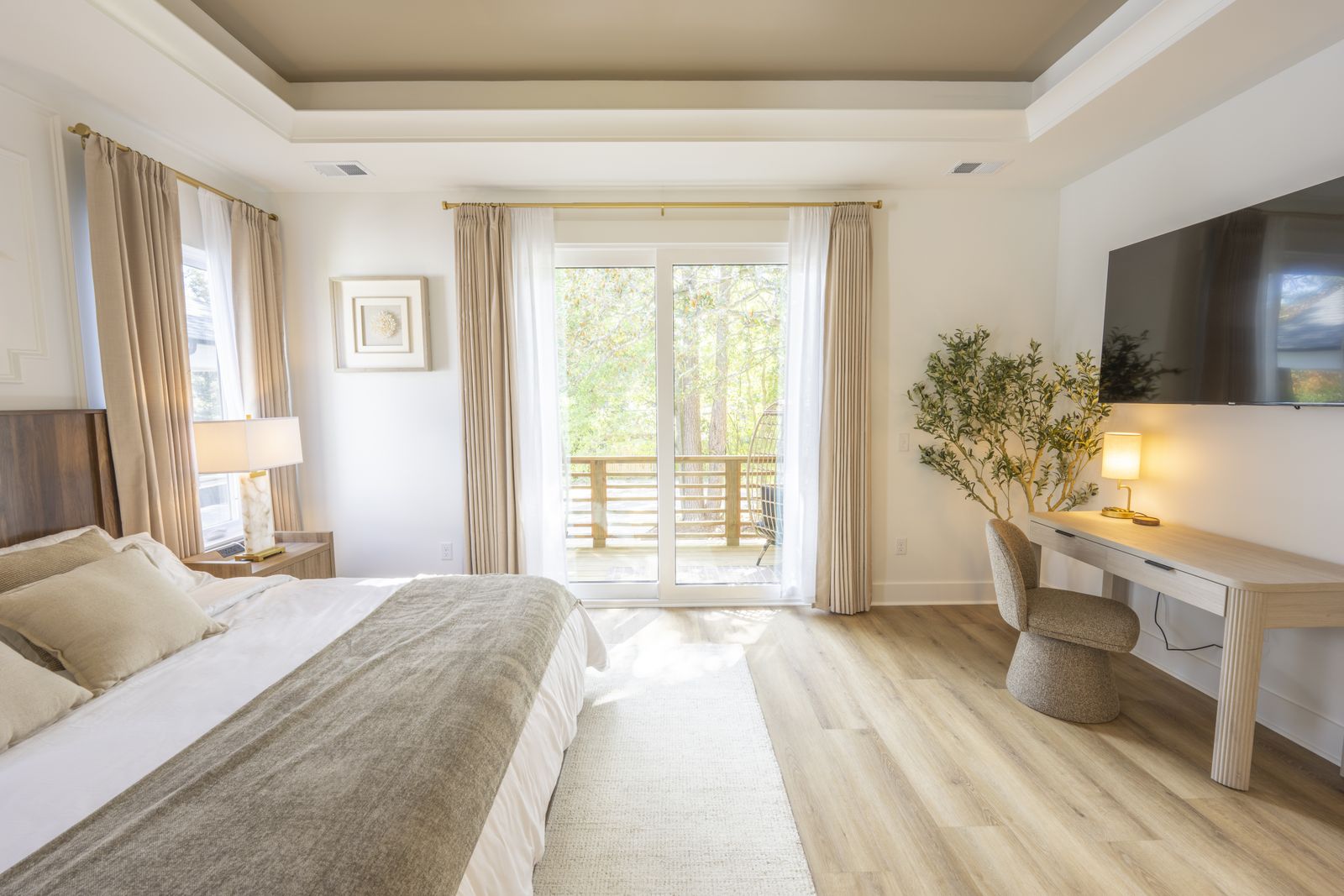Primary suite with desk, TV, and balcony doors