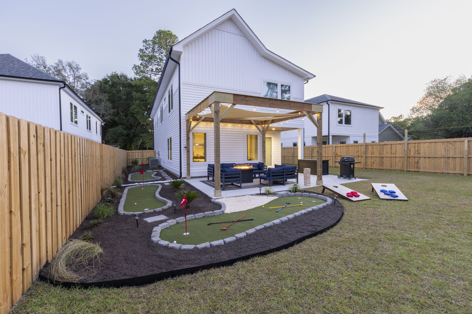Wide view of the backyard with winding putting greens edged in stone